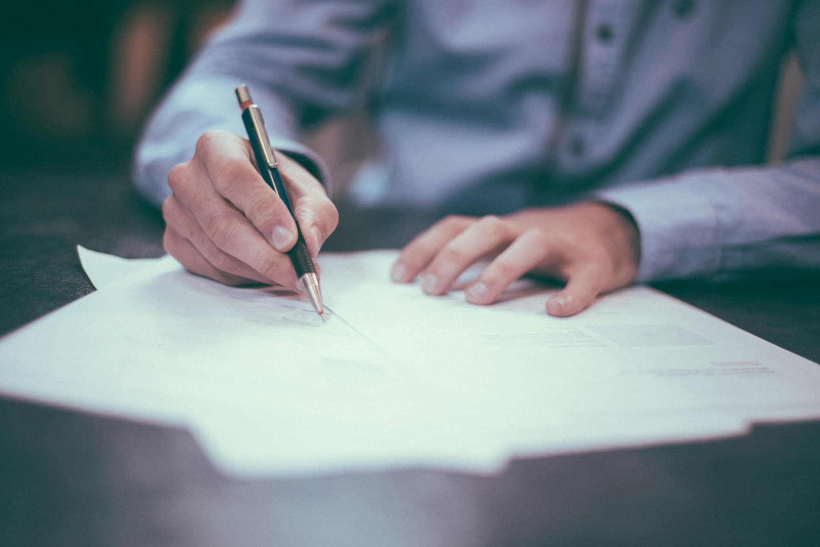 Persona firmando un contrato laboral sobre un escritorio