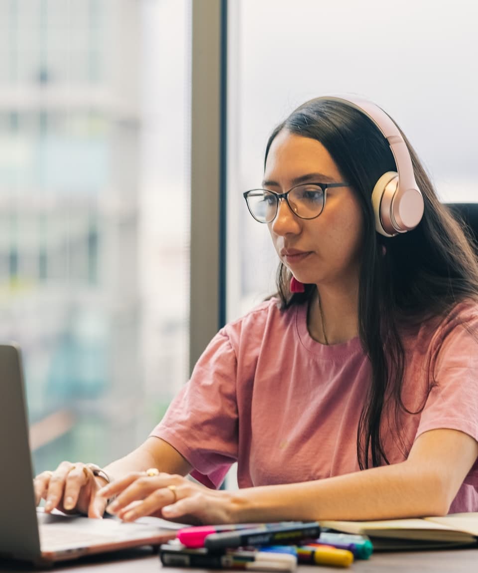 Trabajadora completando un curso de AulaZero con audífonos en su escritorio