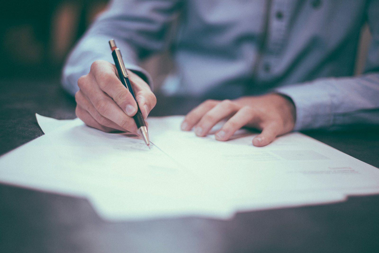 Persona firmando un contrato laboral sobre un escritorio